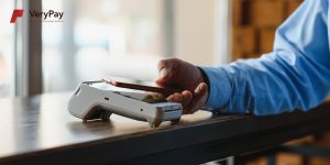 A customer using their phone to tap on a POS device that has VeryPay's white-label. 